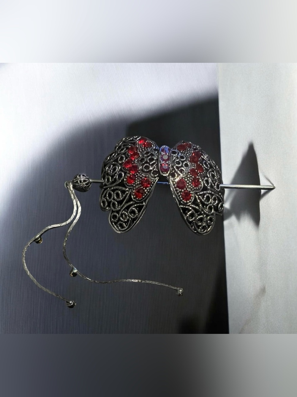 A vintage filigree butterfly hair accessory with red and purple stones.